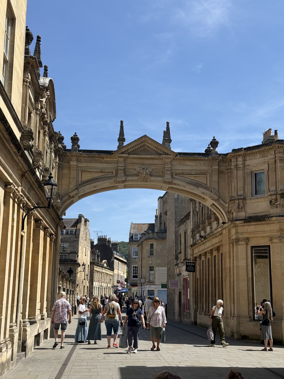 A Georgian archway spanning a street of honey-coloured stone in Bath