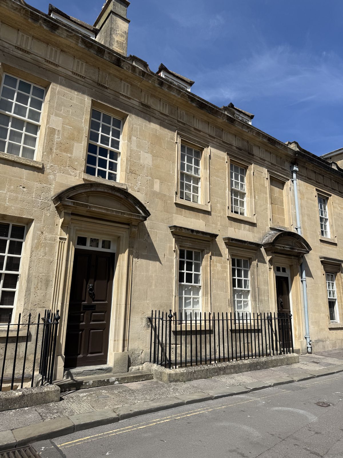 A terrace of Georgian doorways in Bath, honey-coloured stone and iron railings on the kind of street Jane Austen walked daily
